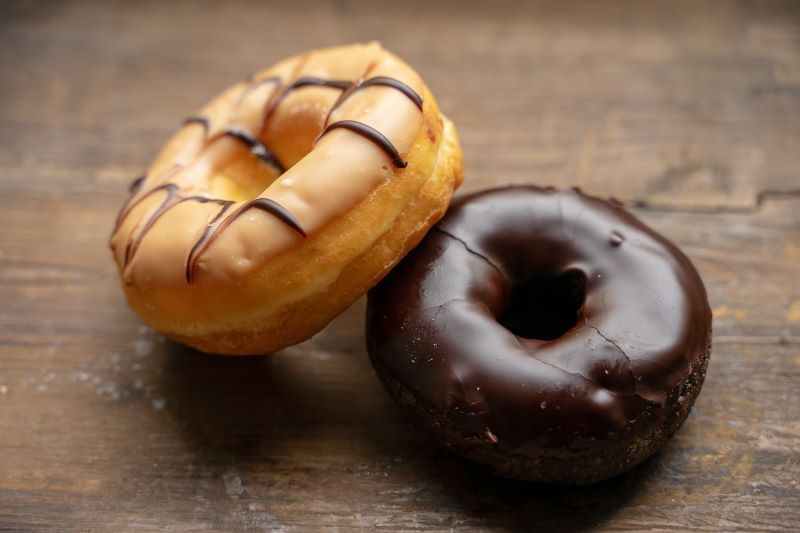 Two glazed ring doughnuts. One coffee glazed the other chocolate glazed.