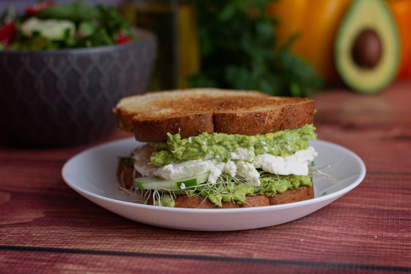 Tosted white bread sandwich with avacado and soft cheese filling.
